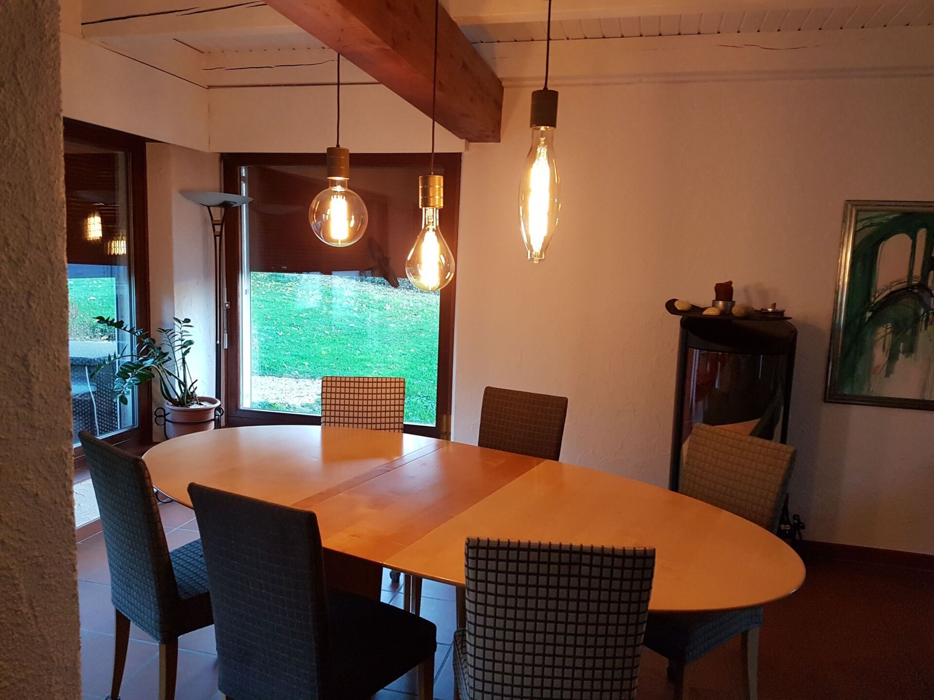 Ein Esszimmer mit Tisch und Stühlen und von der Decke hängenden Lichtern