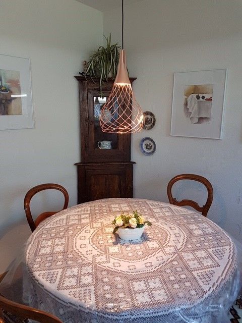 Ein runder Tisch mit einer Spitzentischdecke und einer Schale mit Blumen darauf
