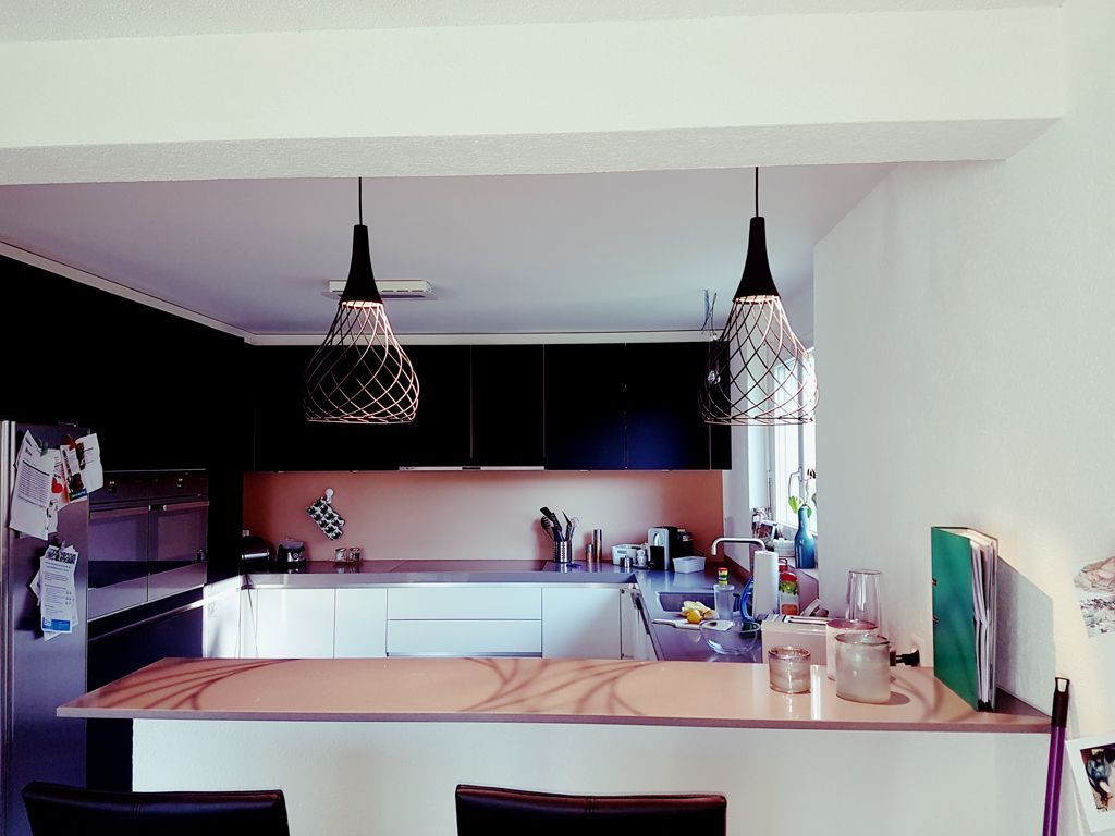 Eine Küche mit schwarzen Schränken und weißen Arbeitsplatten