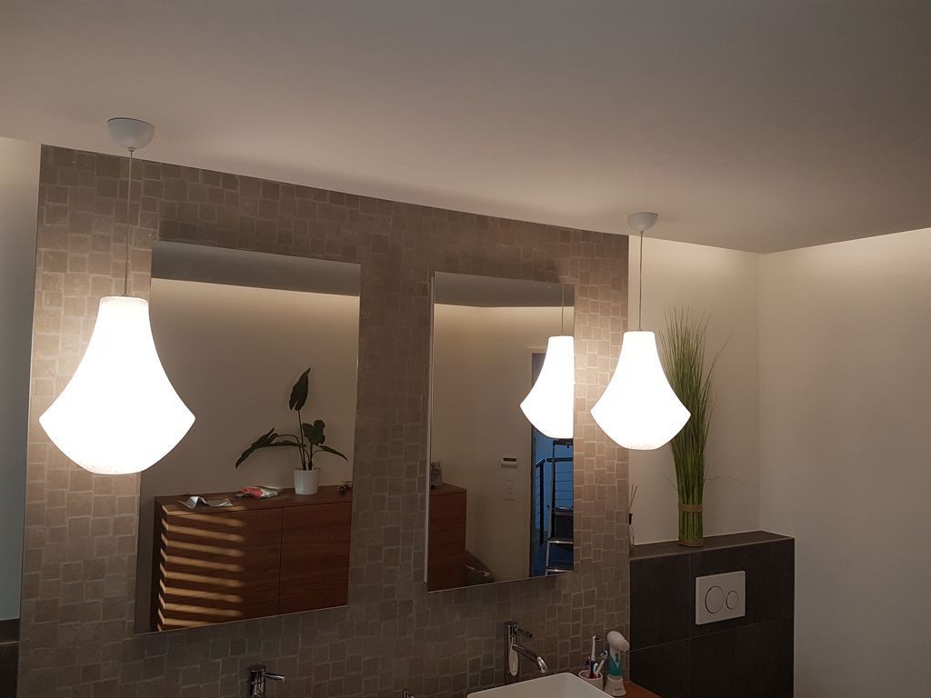 Ein Badezimmer mit zwei Spiegeln und zwei von der Decke hängenden Lampen