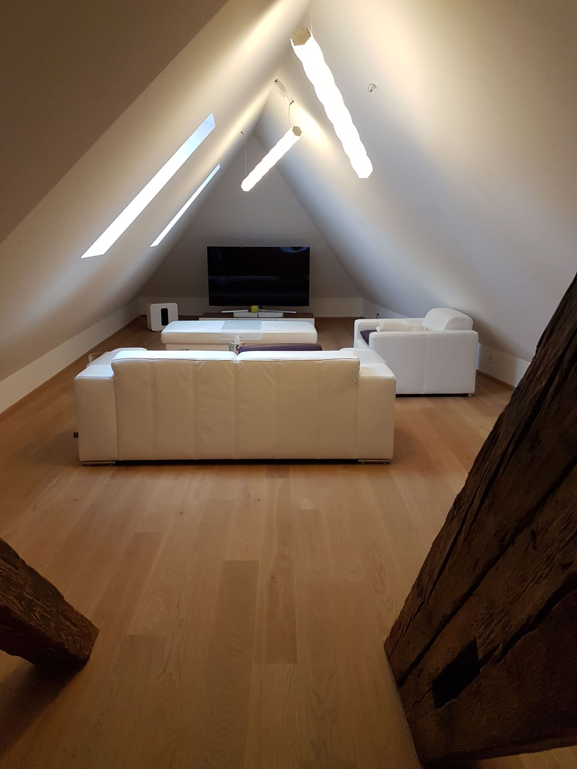 Ein Wohnzimmer im Dachgeschoss mit einer Couch und Stühlen