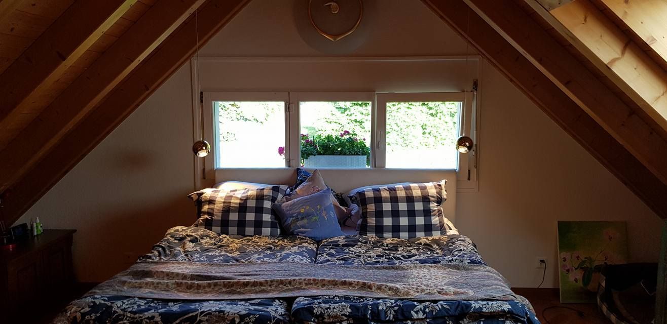 Im Dachgeschoss mit drei Fenstern steht ein Bett.