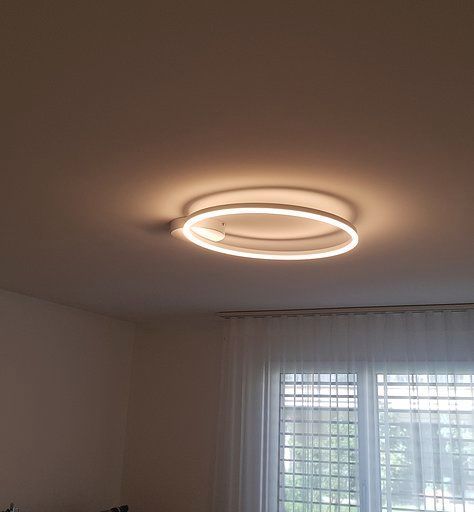 In einem Schlafzimmer neben einem Fenster hängt eine Deckenleuchte von der Decke.