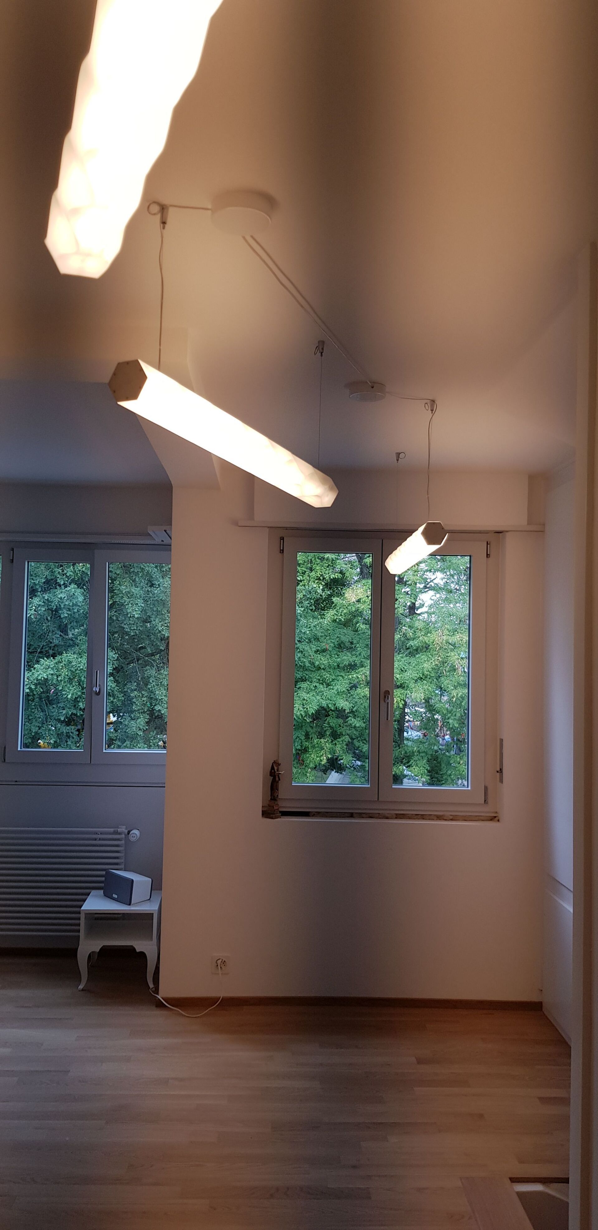 In einem Raum mit einem Fenster hängen zwei Lampen von der Decke.