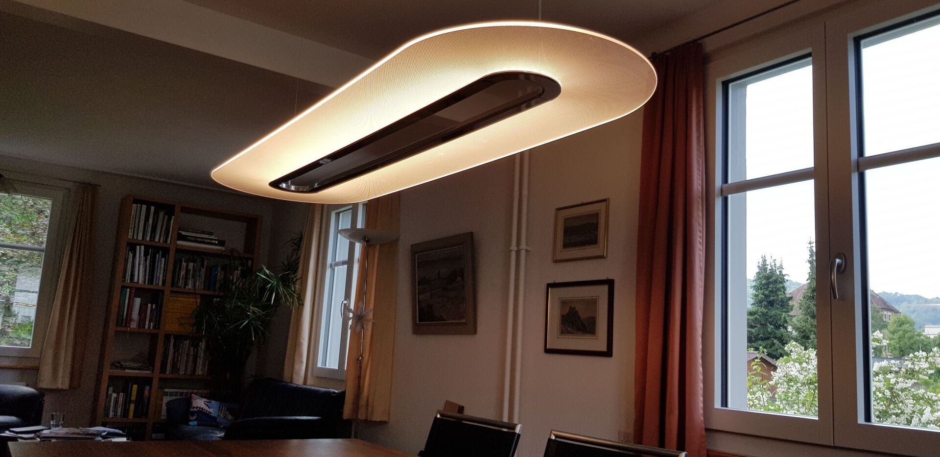 Ein Wohnzimmer mit einem Tisch und Stühlen und einer großen Lampe, die von der Decke hängt.