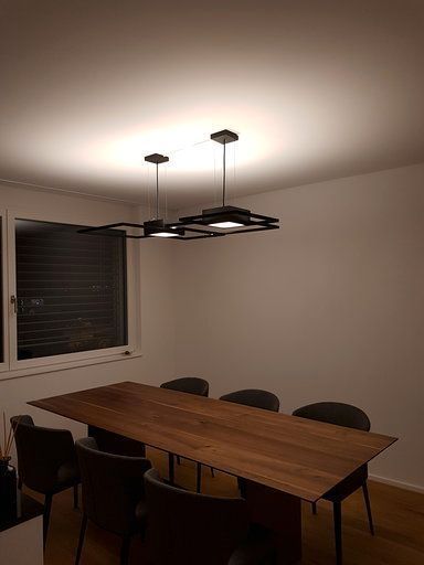 Ein Esszimmer mit einem Holztisch und Stühlen und einem Kronleuchter, der von der Decke hängt.