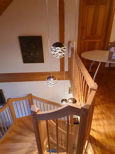 Eine Holztreppe mit einem Tisch im Hintergrund und einem Gemälde an der Wand.