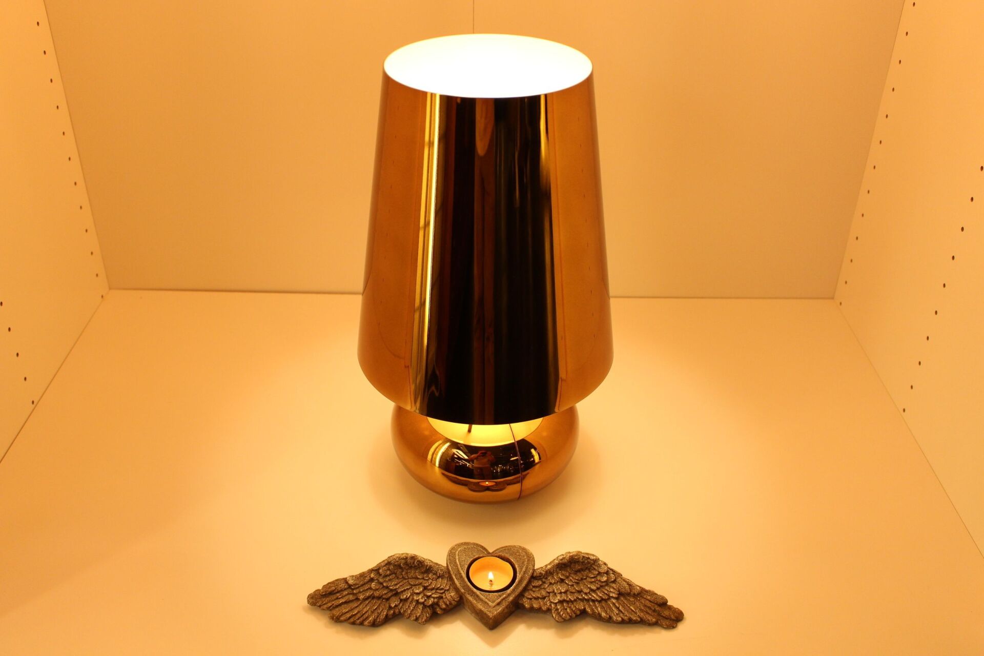 Eine goldene Vase mit einem Herz und Flügeln daneben