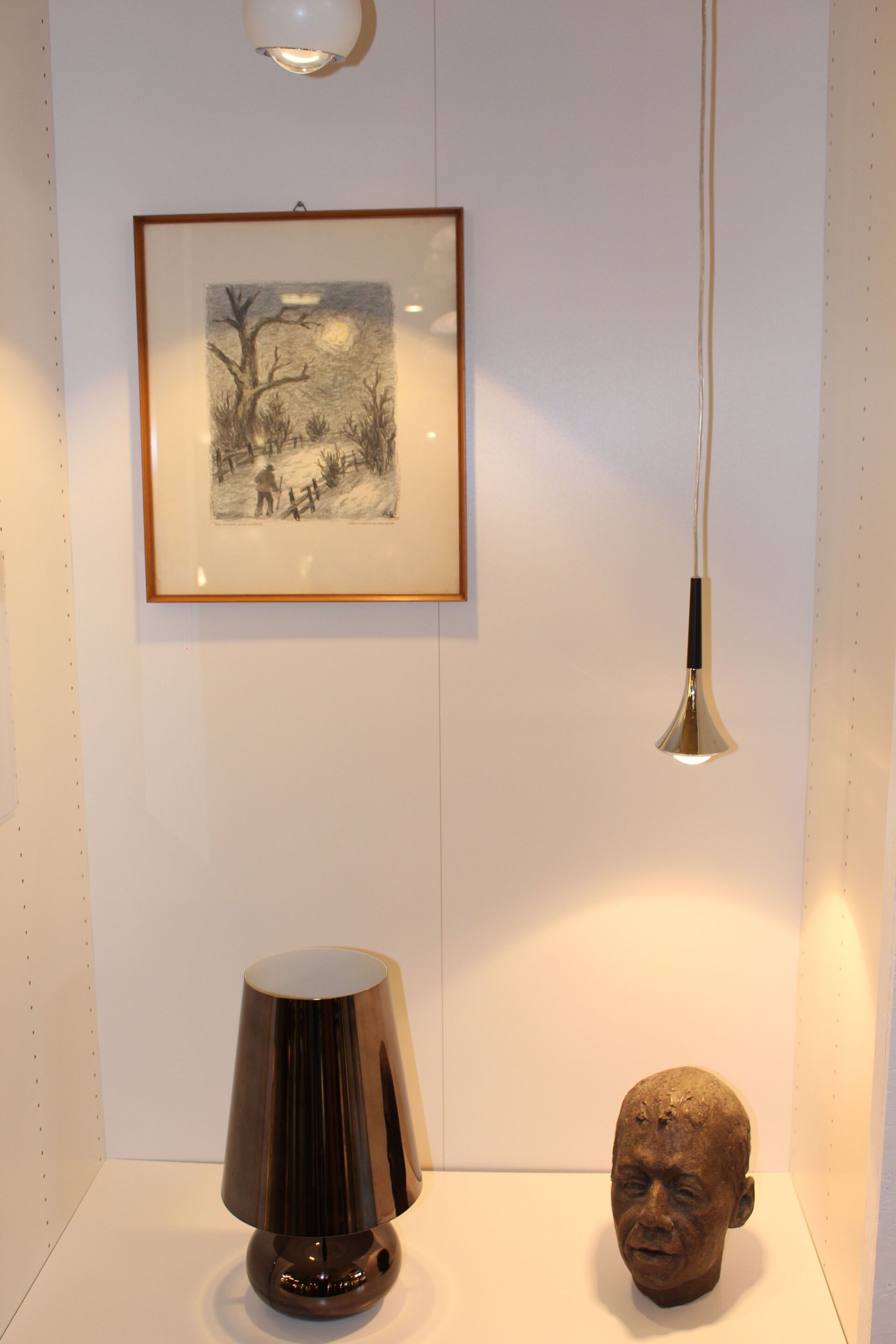 Eine Statue eines Männerkopfes sitzt auf einem Tisch neben einer Lampe.