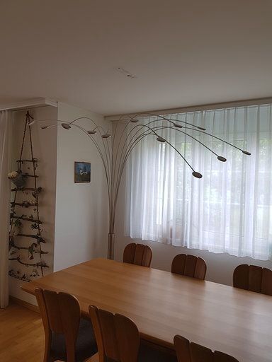 Ein Esszimmer mit einem Holztisch und Stühlen und einer Lampe, die von der Decke hängt.