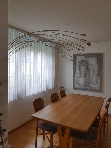 Ein Esszimmer mit einem Holztisch und Stühlen und einem Gemälde an der Wand.