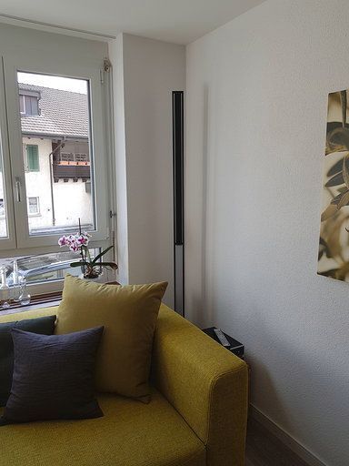 Ein Wohnzimmer mit einer gelben Couch und einem Fenster.