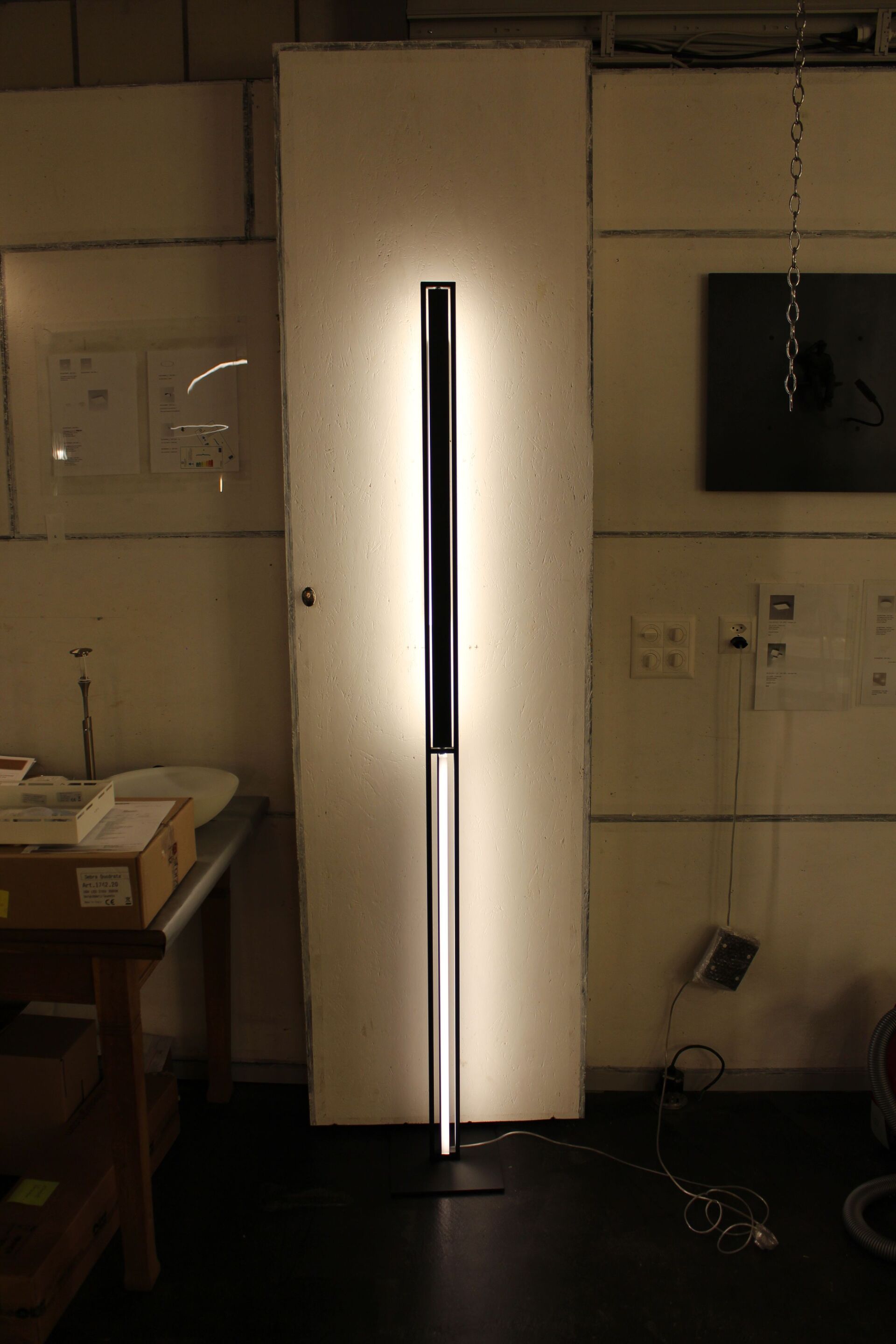 In einem Raum neben einer Tür brennt eine Lampe.