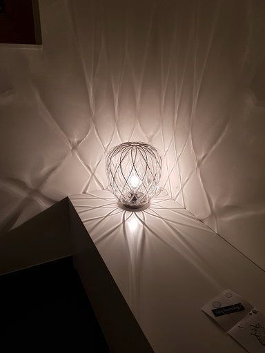 In einem dunklen Raum steht eine Lampe auf einem Tisch.