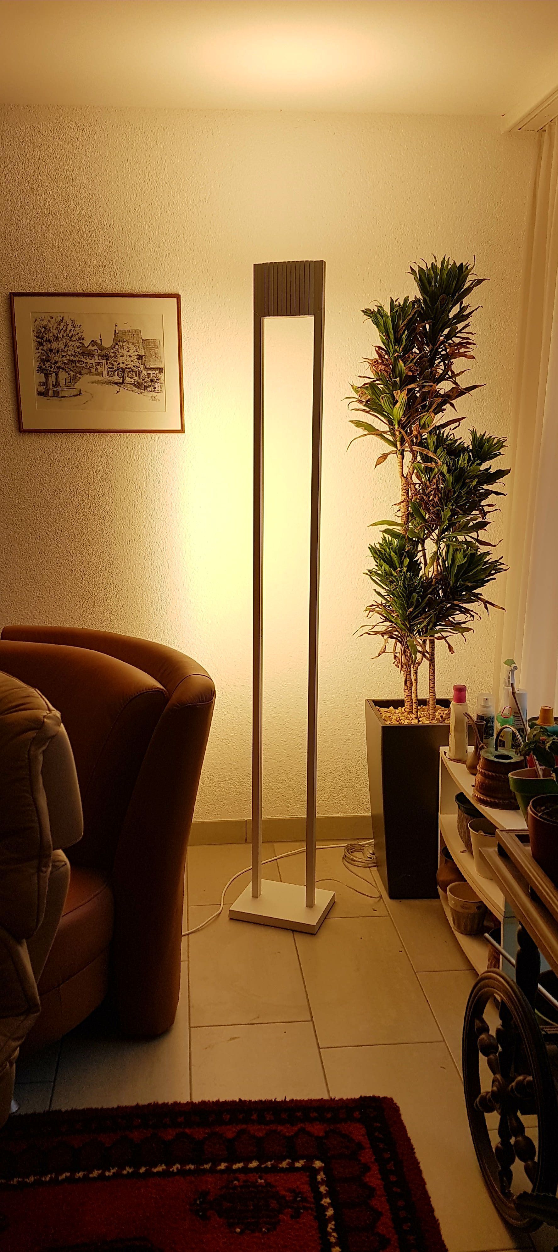 Ein Wohnzimmer mit einer Lampe, einem Stuhl, einem Teppich und einem Weihnachtsbaum.