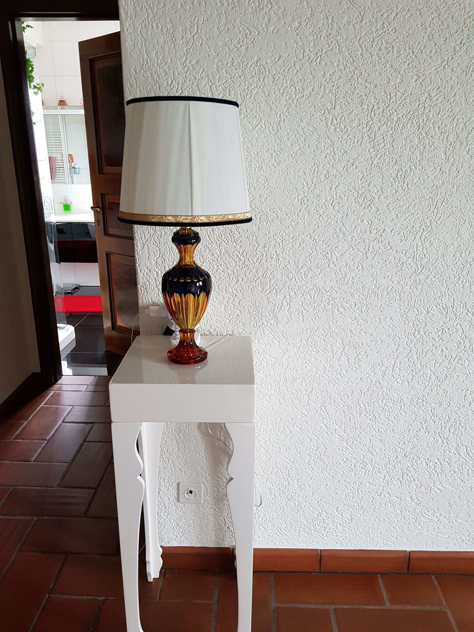 Eine Lampe steht auf einem weißen Tisch vor einer Wand.