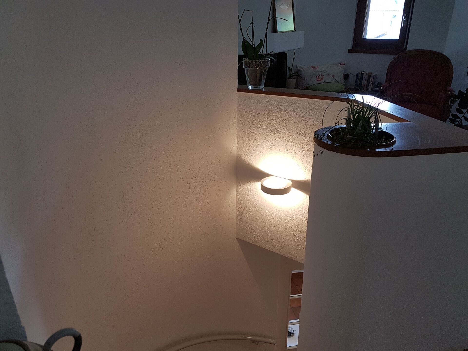 Eine weiße Wand mit einer Lampe darauf in einem Raum.