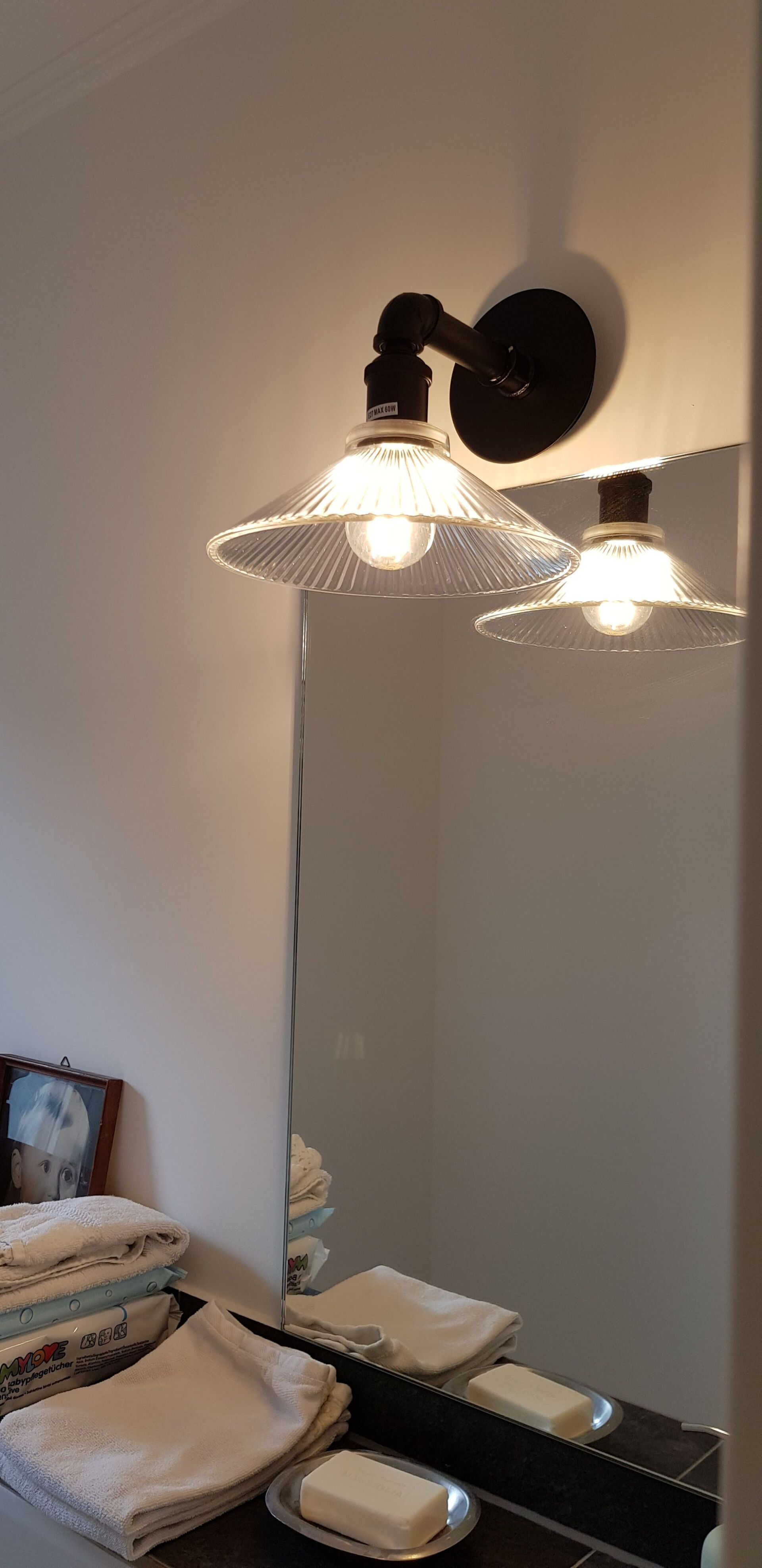 Ein Badezimmerspiegel mit zwei Lichtern darauf und einer Seifenschale.