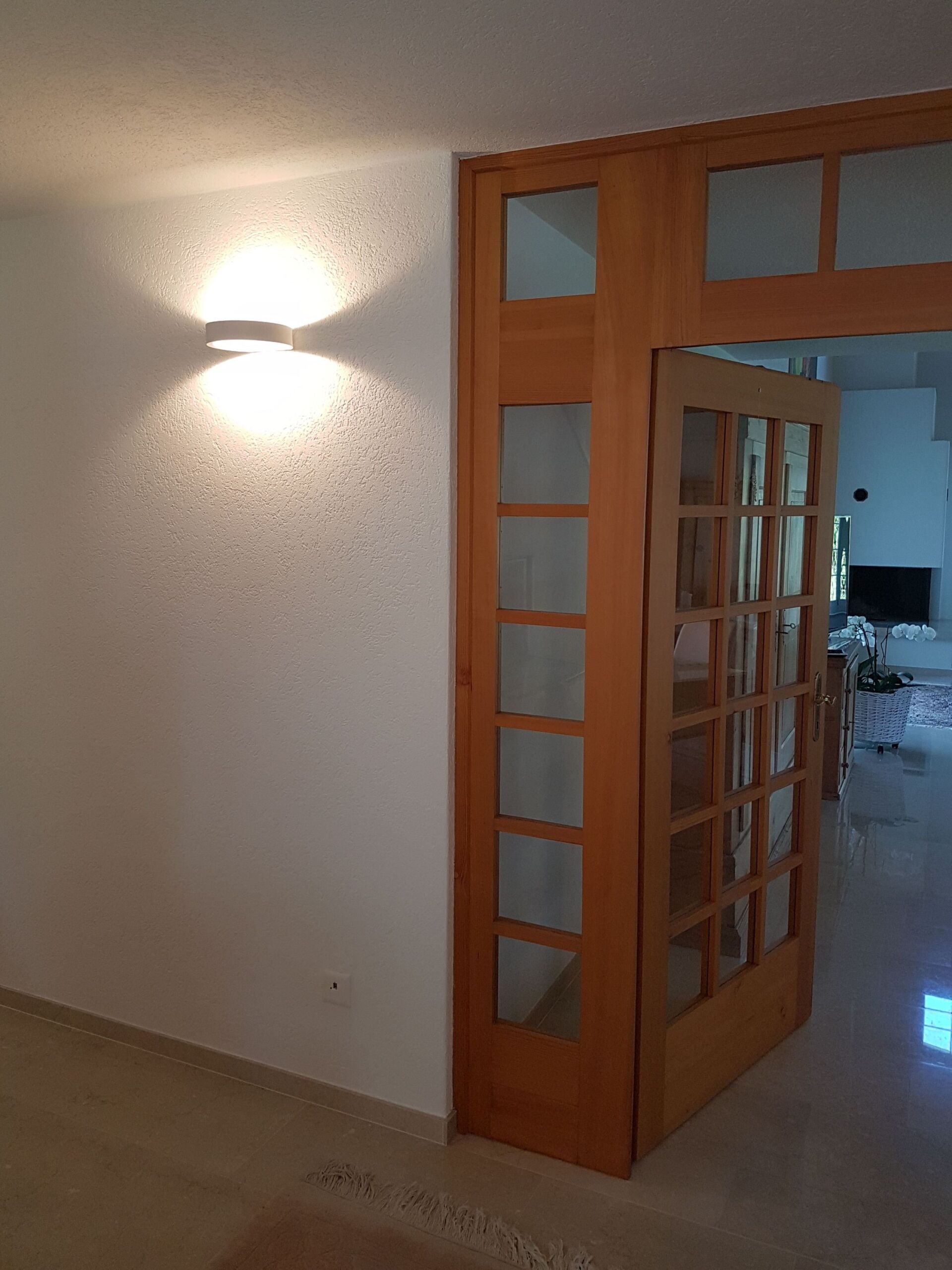 Ein Raum mit einer Holztür und einem Licht an der Wand.