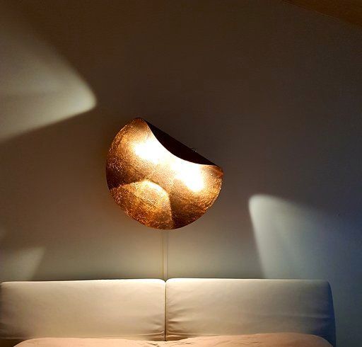 Ein Bett mit einer Lampe an der Wand darüber