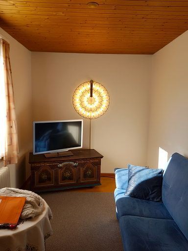 Ein Wohnzimmer mit Couch, Fernseher und Lampe.