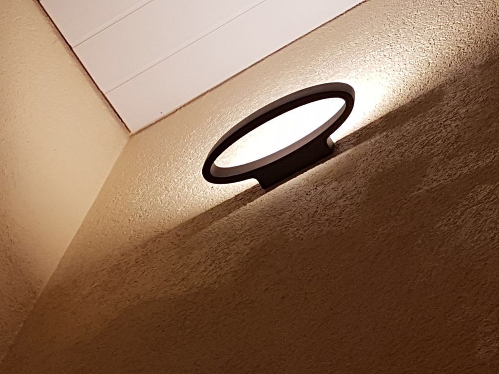 In einem Raum scheint ein Licht auf eine Wand.