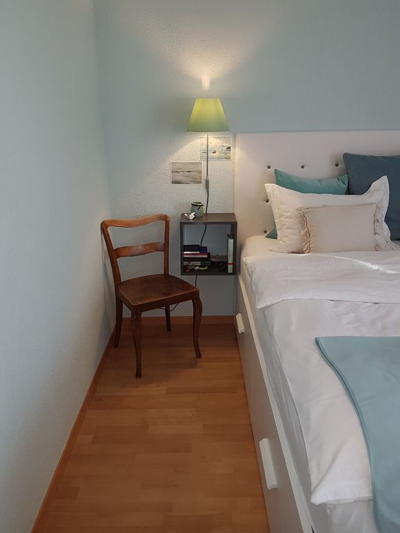 Ein Schlafzimmer mit einem Bett, einem Stuhl und einer Lampe