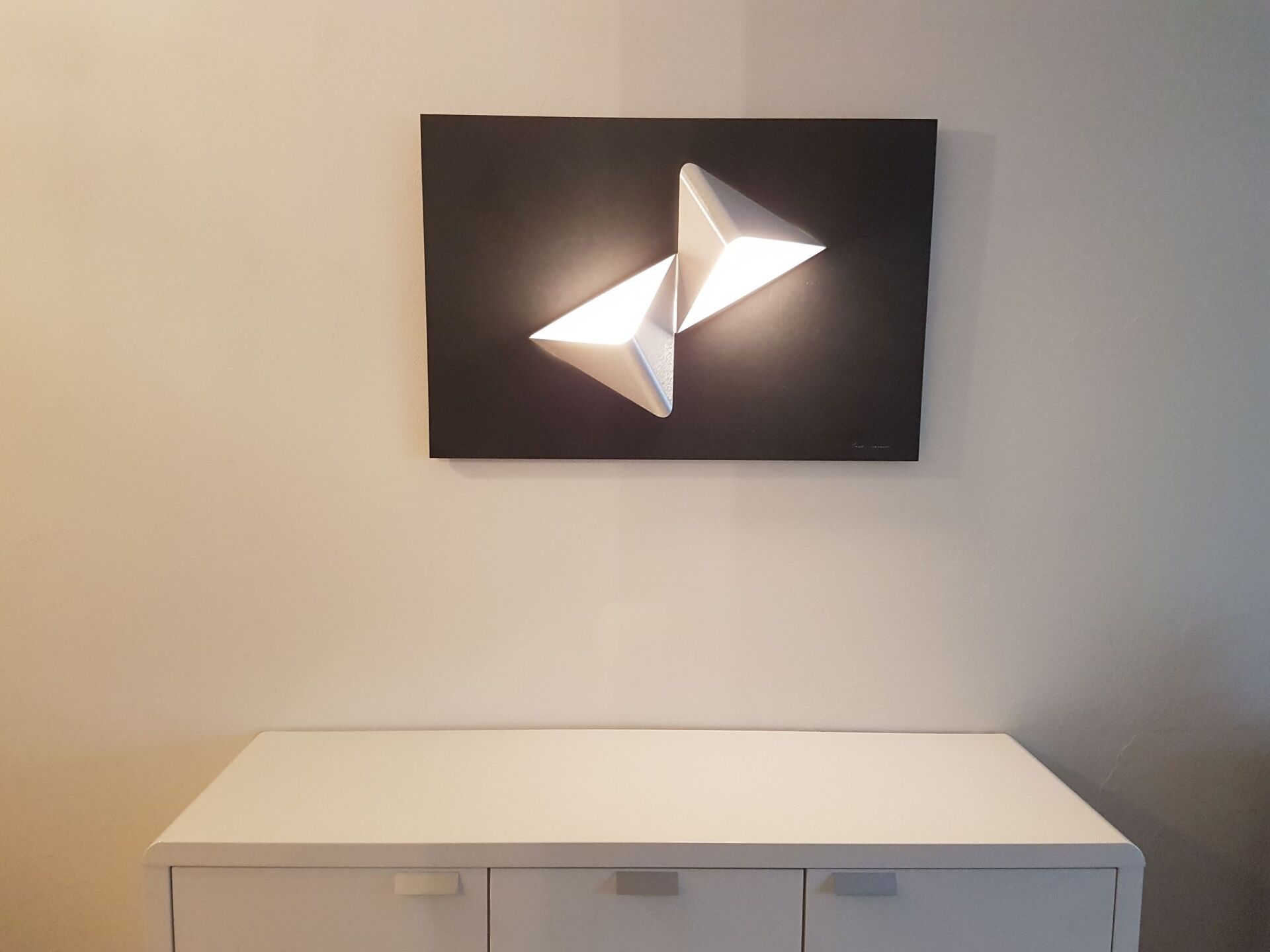 Eine weiße Kommode mit einem Bild an der Wand darüber