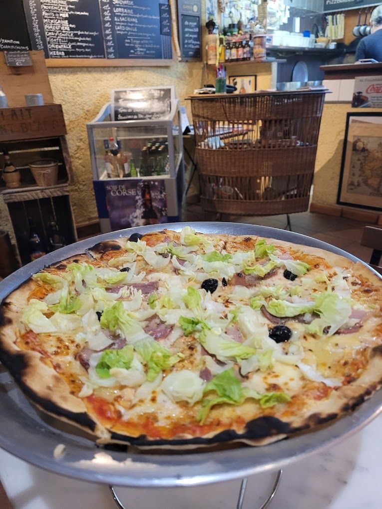 Une pizza à la salade, au jambon et aux olives