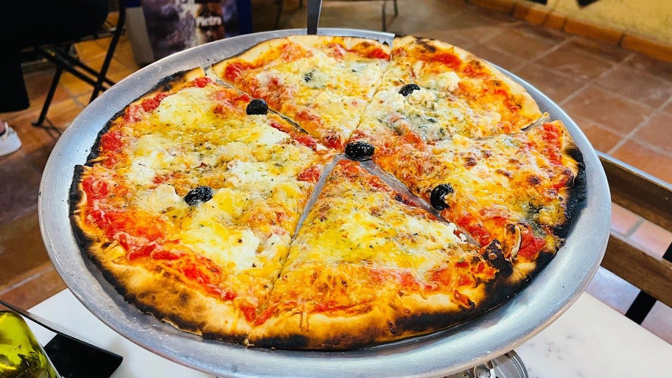 Une pizza base tomate au fromage en terrasse
