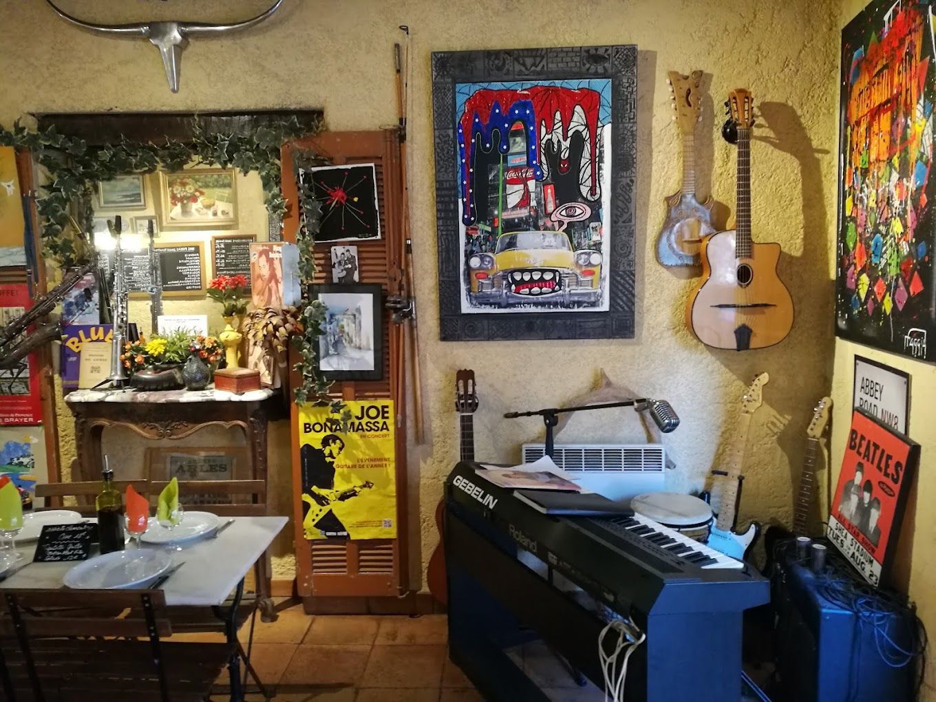 L'intérieur du restaurant avec un piano, une guitare et des peintures au mur