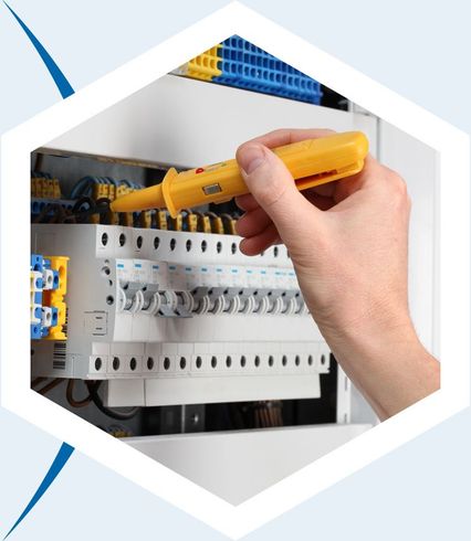 Une main utilise un testeur de tension jaune pour vérifier les connexions électriques d'un tableau de disjoncteurs.