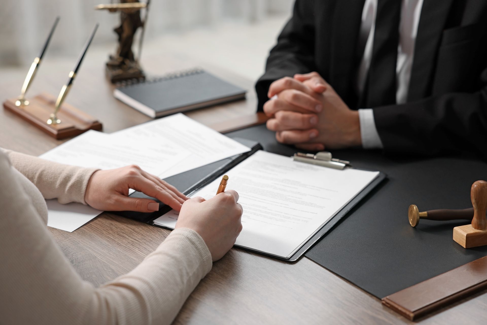 Bureau d'avocat avec marteau, balance de la justice et une personne écrivant en arrière-plan.