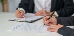 Poignée de main d'affaires au-dessus d'un bureau, avec un marteau de juge et la balance de la justice au premier plan.