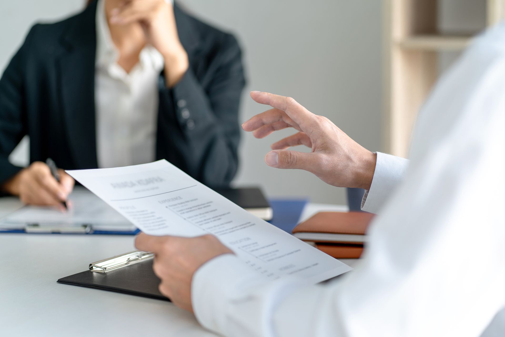 Deux personnes en réunion, examinant des documents de part et d'autre d'un bureau.