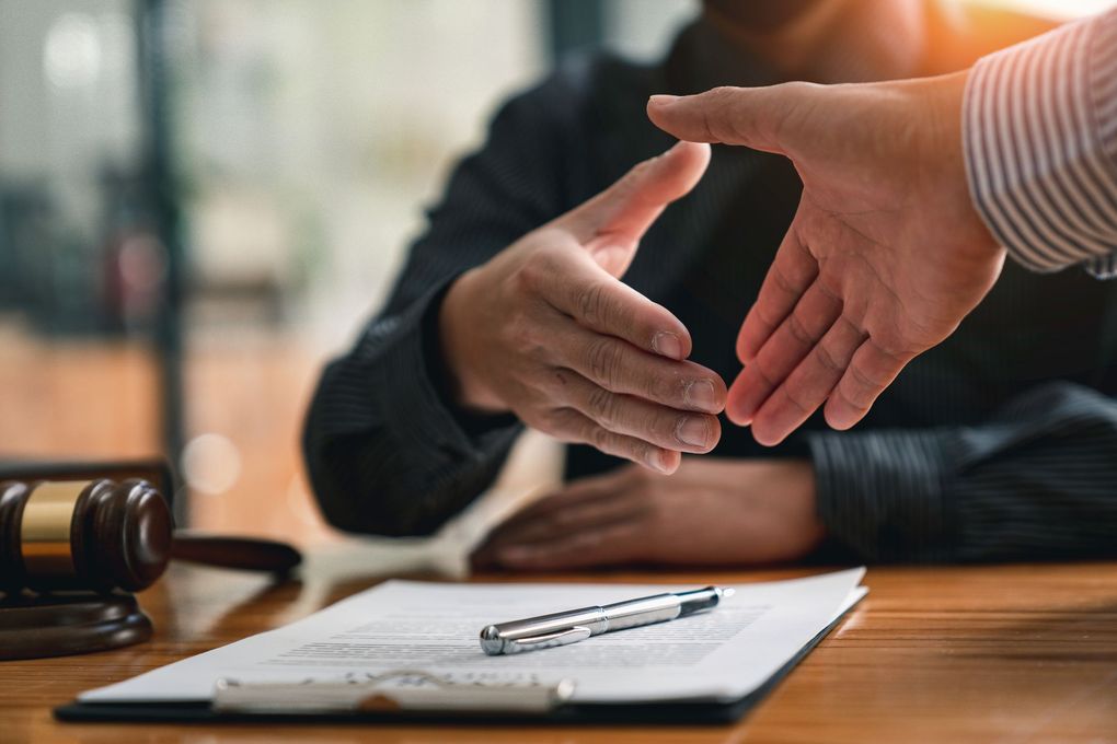 Marteau et balance sur le bureau lors d'une réunion avec un avocat, en présence d'un ordinateur portable et de documents.