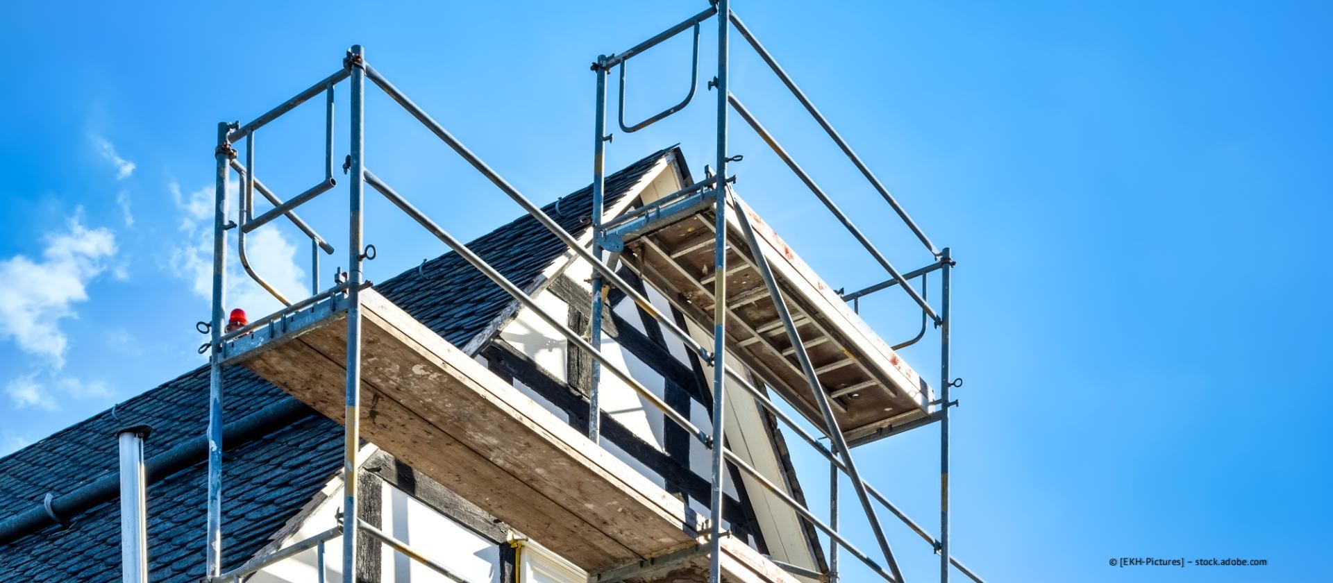 Baugerüst auf einem im Bau befindlichen Dach vor blauem Himmel