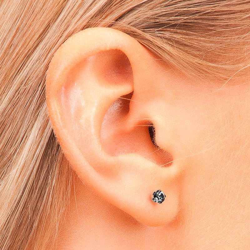 Nahaufnahme eines Frauenohrs mit einem kleinen, dunklen Ohrstecker. Blondes Haar umrahmt das Ohr.