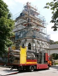 Ein roter Lastwagen steht vor einem im Bau befindlichen Gebäude.