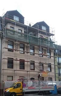 Ein gelber Lastwagen steht vor einem im Bau befindlichen Gebäude.