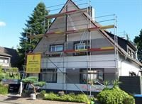 Ein Haus mit einem Gerüst darum wird gestrichen.