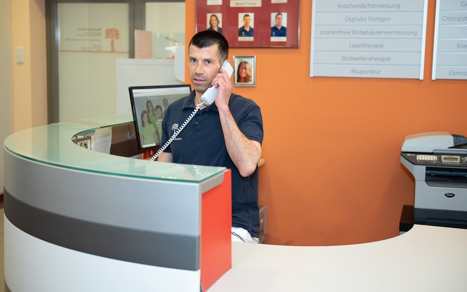 Foto | Ein Mitarbeiter an der Rezeption, der ein Telefonat führt.