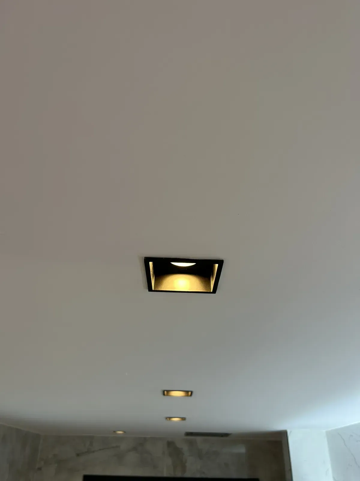 Luces de techo empotradas en fila sobre un techo blanco.