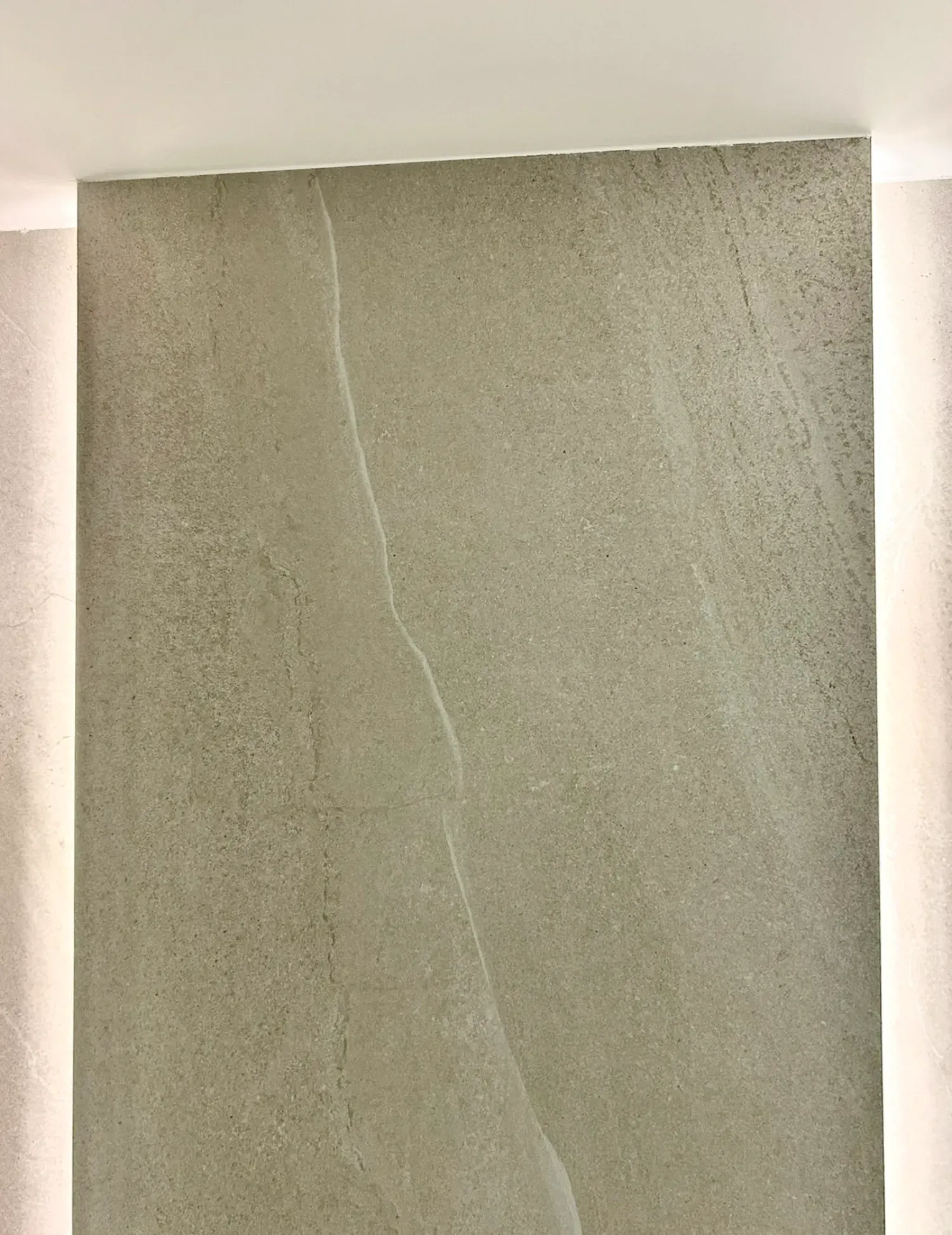 Muro de piedra gris con una grieta blanca. Tiras de luz LED verticales a ambos lados.