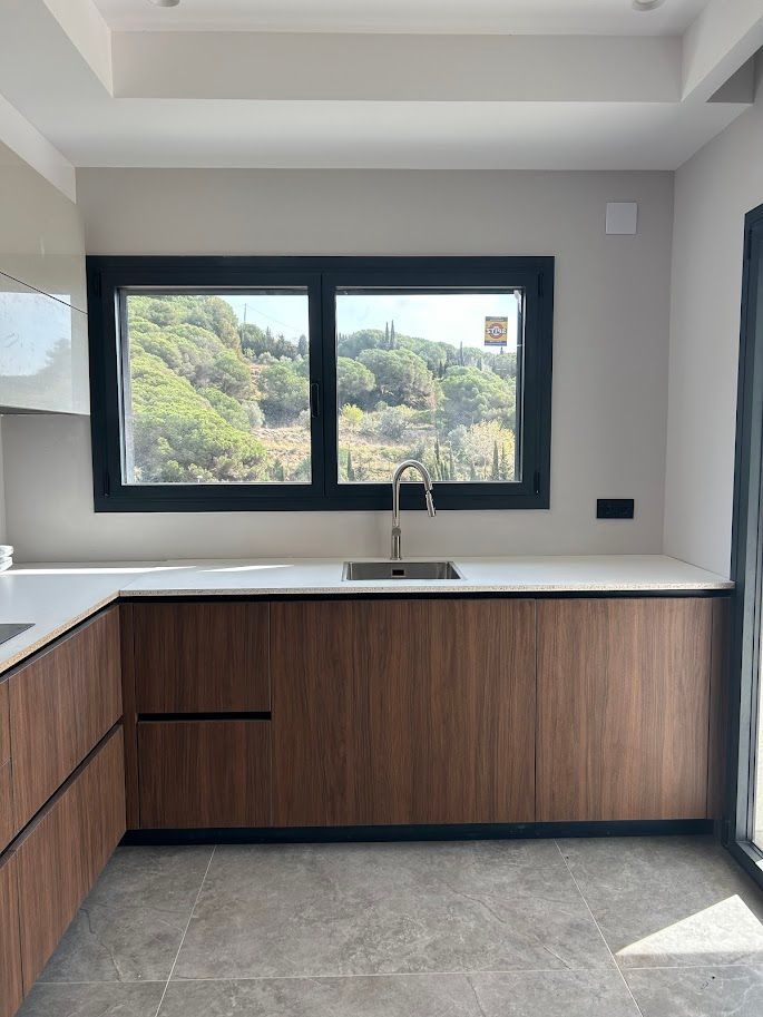 Baño con espejo ovalado retroiluminado, azulejos en espiga gris, lavabo blanco y tocador de madera.