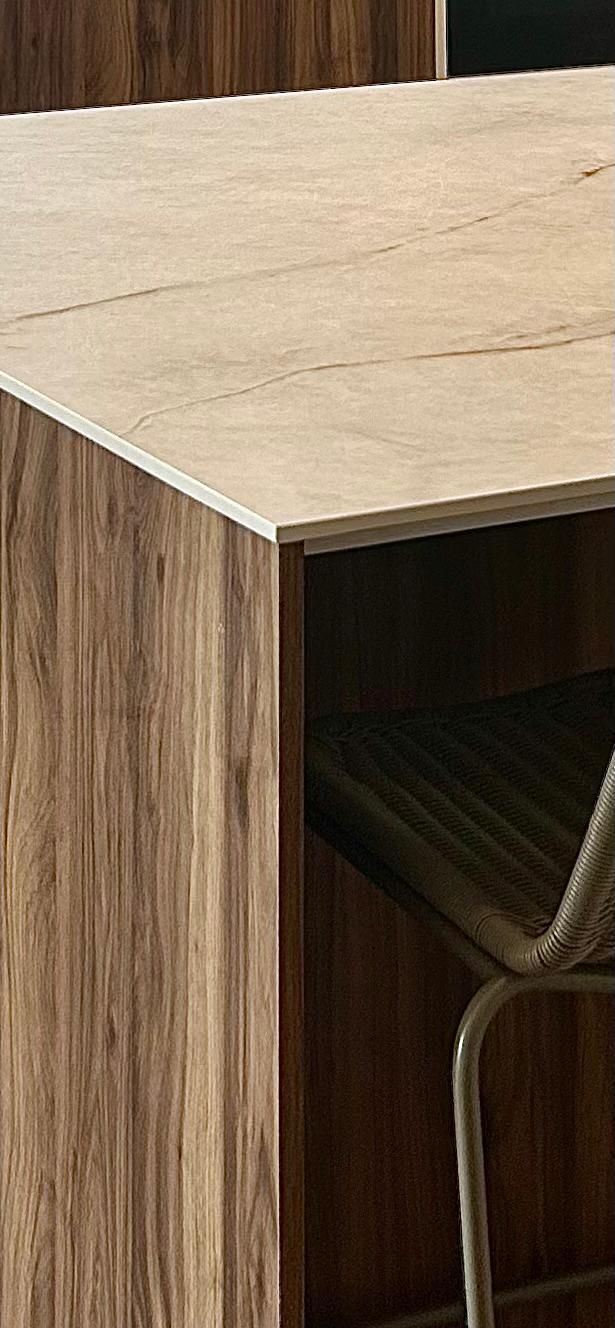 Cocina moderna con gabinetes grises, detalles en negro y vitrinas con frente de vidrio con iluminación.