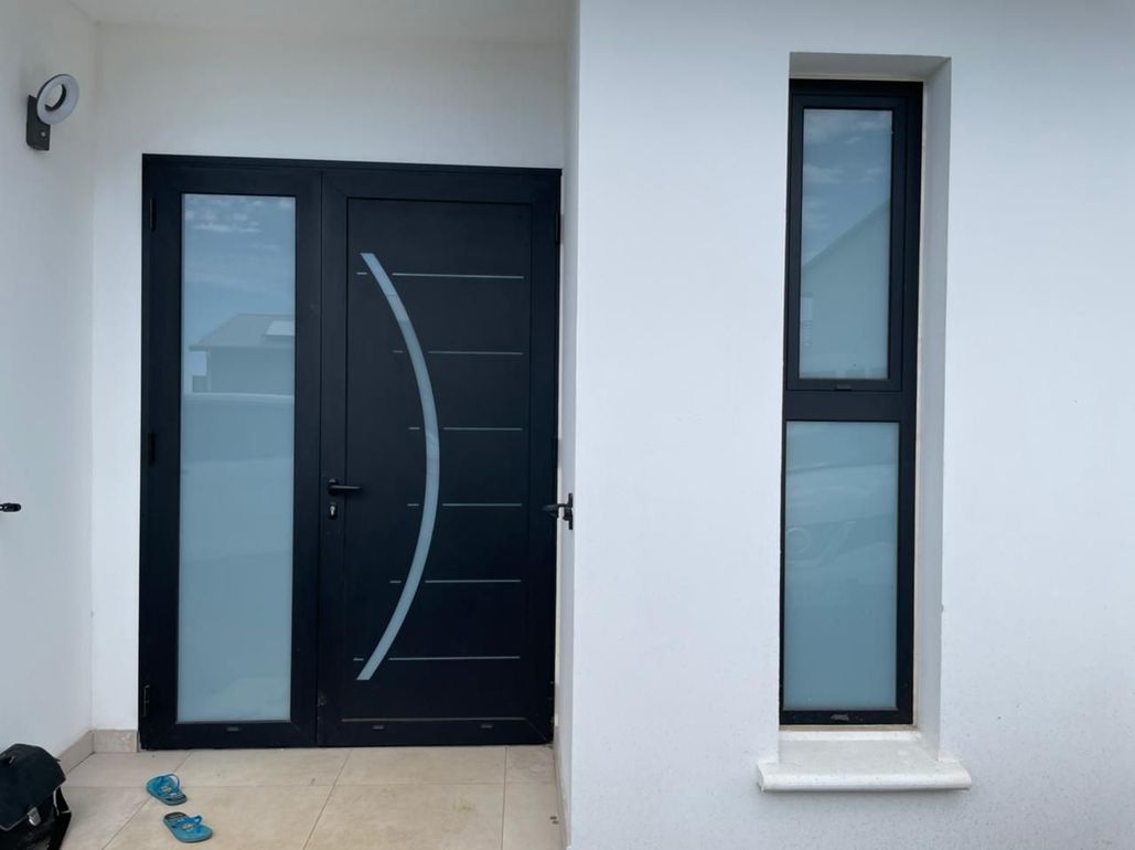 Pose de porte d'entrée sombre, panneau latéral en verre dépoli et fenêtre étroite