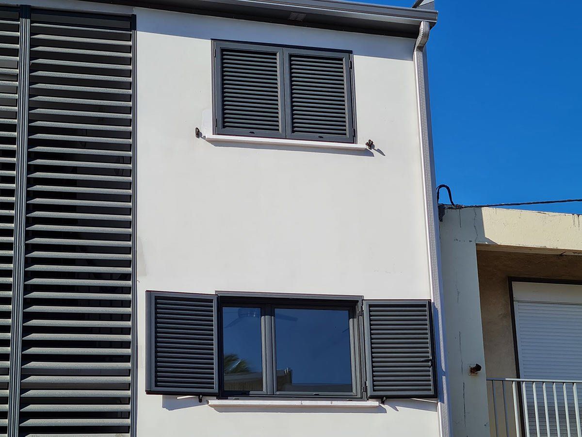 Façade d'un immeuble et ses volets sombres