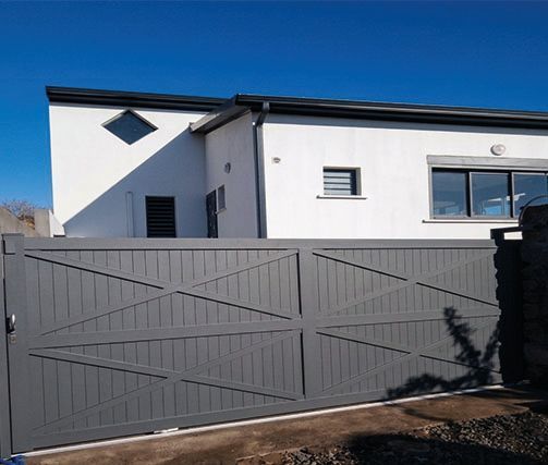 Maison blanche moderne derrière un portail métallique gris