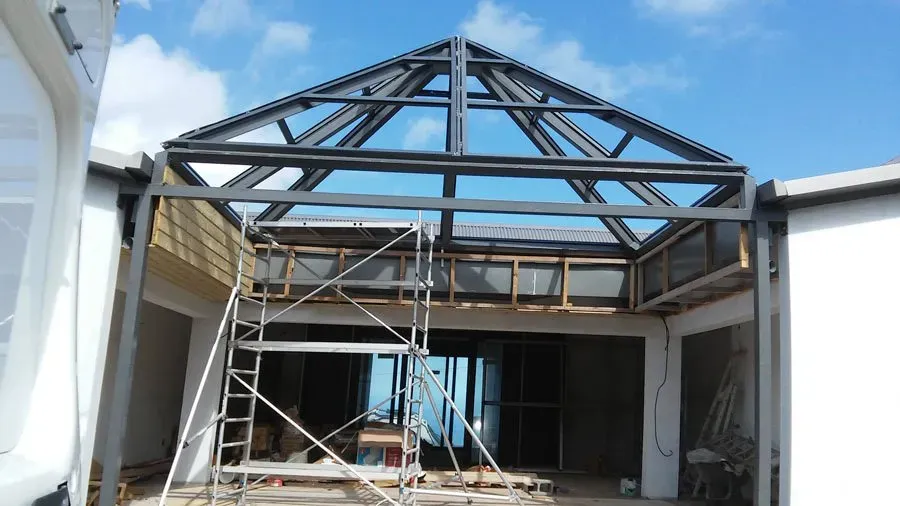 Maison en construction avec un toit pyramidal en aluminium et en verre